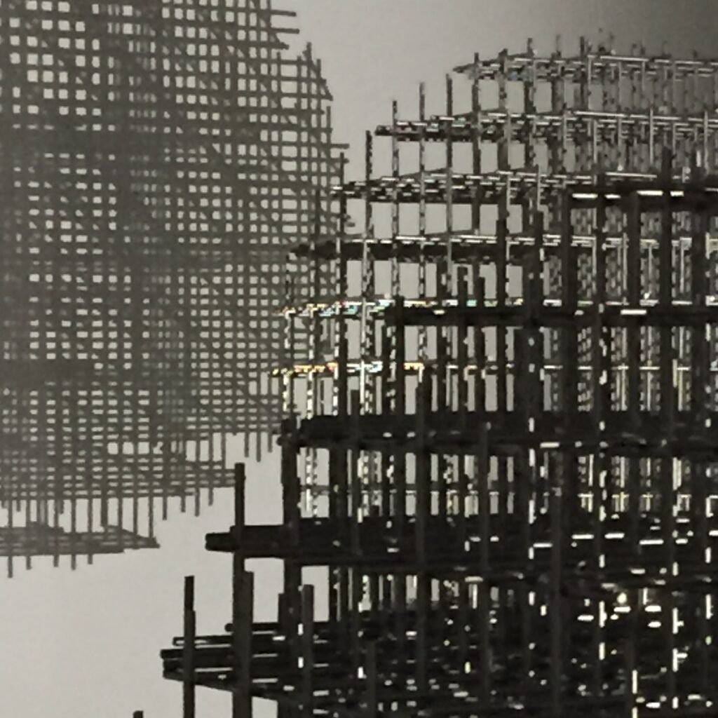 Layered structural framework with repeating grids, partially assembled, held in tension.